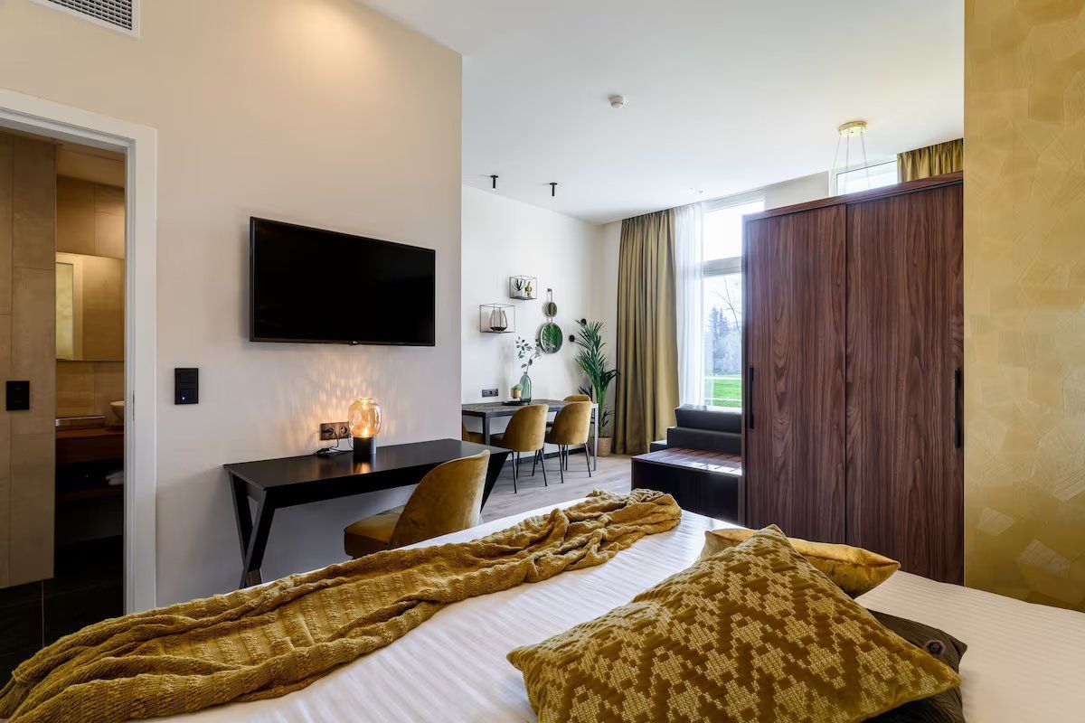 A hotel room with a bed, a desk, a television, and a wardrobe.