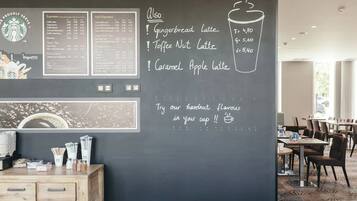 A café with a chalkboard menu listing various coffee and tea options, including iced espresso and hazelnut flavor.