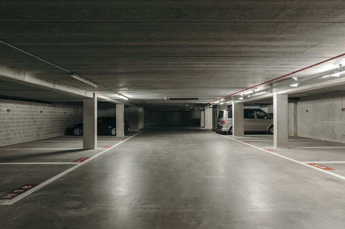 A multi-level parking garage with concrete pillars, marked parking spaces, and overhead lighting.
