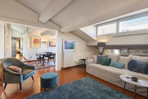 A spacious living area with a high ceiling, a dining table, a sofa, and a small round table with a lamp. - Apartment 'Corte Regia' with Air Conditioning (Verona)