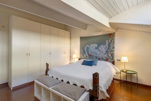 Ein Schlafzimmer mit einem großen Bett, einem Kleiderschrank, einer Bank und einem Bild an der Wand.
