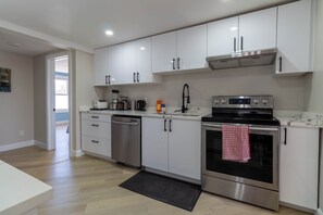 A modern kitchen with stainless steel appliances, white cabinetry, and a black oven with a red and white checkered towel hanging on the handle. - Newly Renovated Quiet 2BR | WiFi, Parking & Heat Included—Sleeps up to 6! (London)
