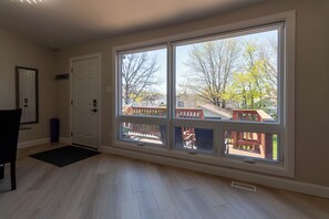 A room with a large window, a door, and a wooden floor. - Newly Renovated Quiet 2BR | WiFi, Parking & Heat Included—Sleeps up to 6! (London)