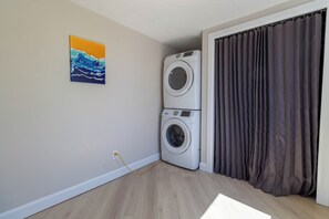 A laundry room with a washing machine and dryer, a power outlet, and a painting on the wall. - Newly Renovated Quiet 2BR | WiFi, Parking & Heat Included—Sleeps up to 6! (London)