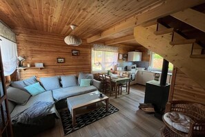A wooden cabin interior with a sofa, dining table, kitchen area, and a staircase. - Holiday home for 6 people Dziwnów (Dziwnów)