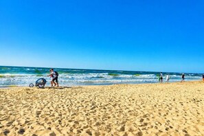 A beach with people walking and a wheelchair on the sand. - Holiday home for 6 people Dziwnów (Dziwnów)