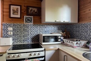 A kitchen with a stove, microwave, and a tiled backsplash. - Holiday home for 6 people Dziwnów (Dziwnów)