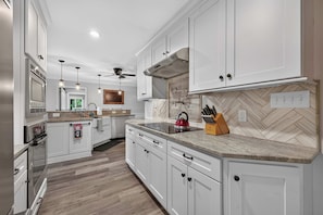 A modern kitchen with white cabinetry, a built-in oven, a microwave, and a kettle on the countertop. - Lake Norman Haven | Private Dock + Lake Views (Denver)