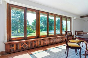 Comedor con ventana grande, banco de madera y sillas.