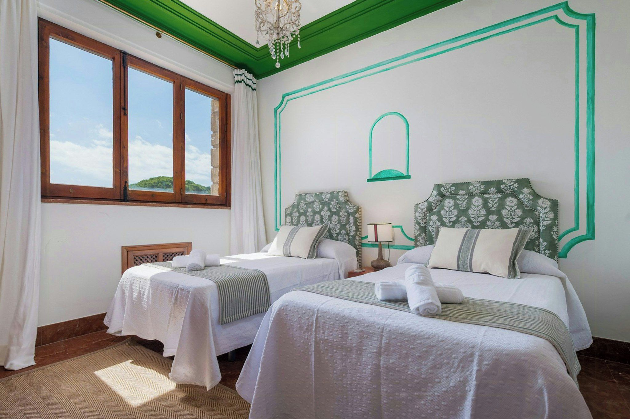 Een hotelkamer met twee bedden, een groot raam en uitzicht op zee.