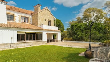 A two-story house with a stone facade, a tiled roof, and a well-maintained lawn.