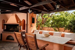 An outdoor patio with a built-in grill, wooden chairs, and a table with cushions. - Seaview Villa with Pool for 10 (Kato Gouves)