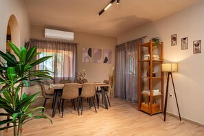 A dining area with a table and chairs, a bookshelf, and a lamp. - Seaview Villa with Pool for 10 (Kato Gouves)