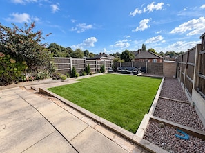 A well-maintained backyard with a lawn, patio furniture, and a wooden fence. - Family Home | Free Secure Parking | Pets Allowed - Pass the Keys (Salford)