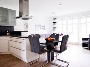 A modern kitchen with a central island, white cabinetry, and a black countertop. - Paula Apartment 2 (Wyk auf Foehr)