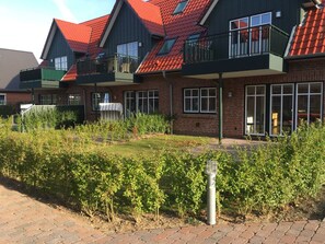 A residential building with multiple balconies, brick walls, and a paved walkway. - Paula Apartment 2 (Wyk auf Foehr)