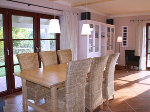 A dining area with a wooden table and wicker chairs, a cabinet with glass doors, and a view through the glass doors. - Holiday Home With 1 Bedroom (Rathmannsdorf)