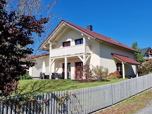 A two-story house with a balcony, a red roof, and a white fence in front. - Holiday Home With 1 Bedroom (Rathmannsdorf)