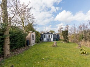 A single-story house with a small attached garage, a front porch with a table and chairs, and a well-maintained lawn. - Holiday Home With 2 Bedrooms (Burgh-Haamstede)