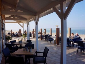 An outdoor seating area with tables and chairs, overlooking a beach. - Holiday Home With 2 Bedrooms (Burgh-Haamstede)