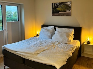 A neatly made bed with white linens, a dark headboard, and two bedside lamps. - Holiday Apartment With 2 Bedrooms (Butjadingen)