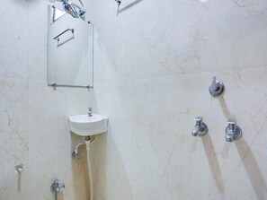 Ein Badezimmer mit weißem Waschbecken, einem Spiegel und einer Duschkabine.