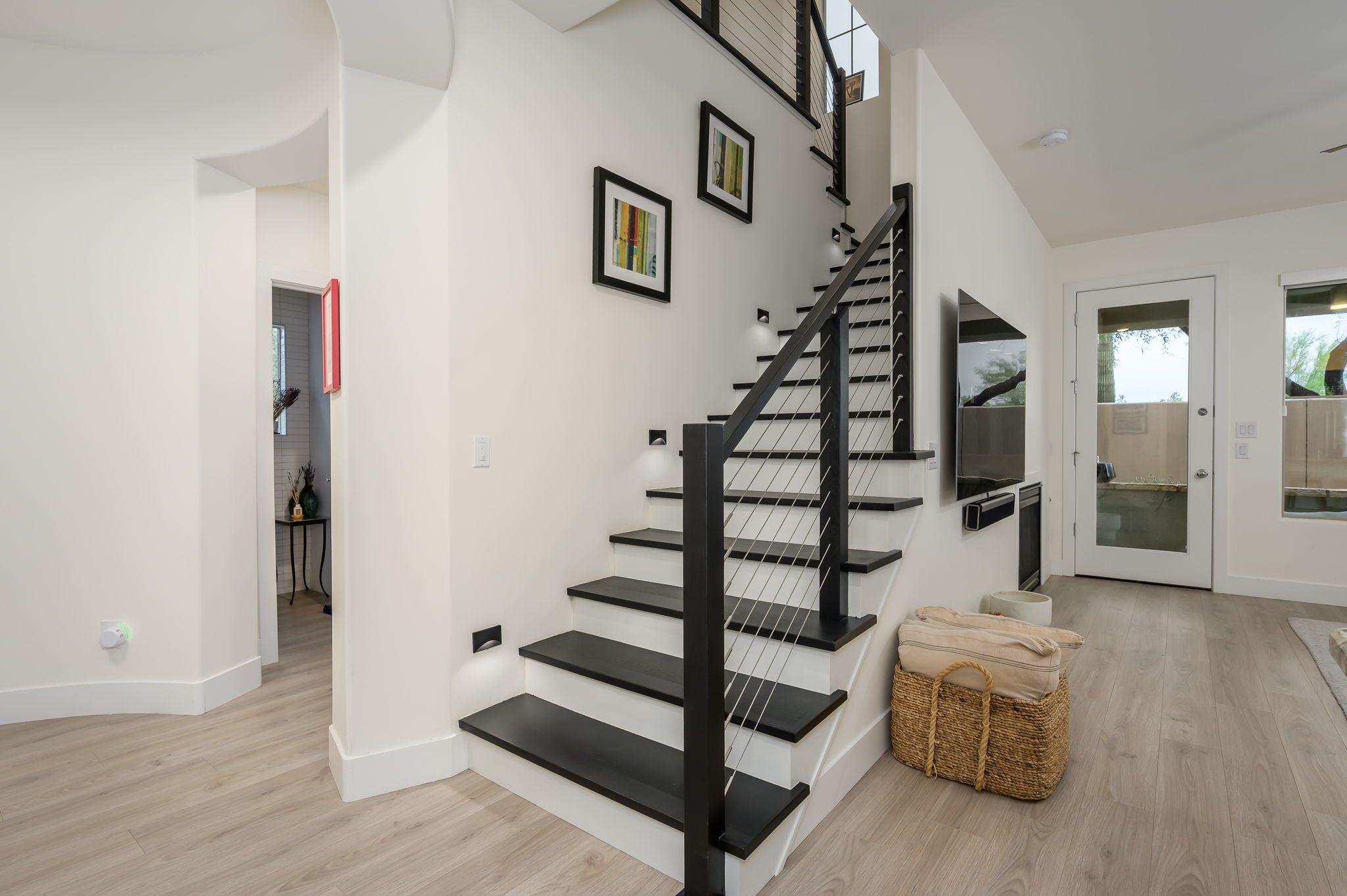 A modern interior with a staircase, a flat-screen TV, and a wicker basket.