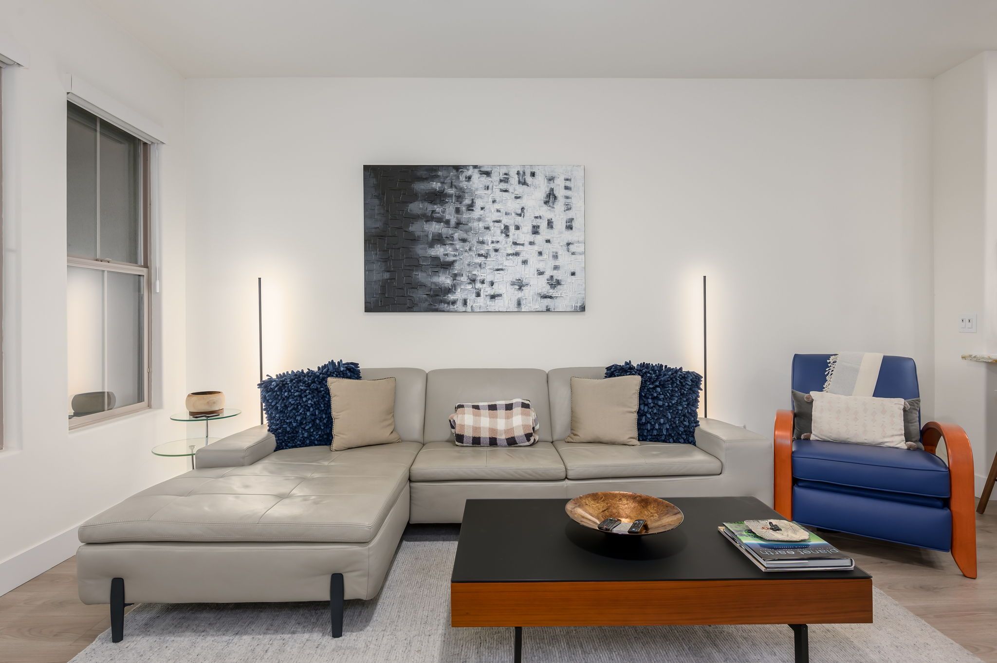 Una sala moderna con un sofá modular, una mesa de centro y un sillón azul.