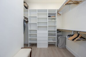 Un vestidor con estantes abiertos, un banco y espacio para colgar ropa.