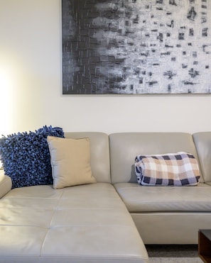 A beige sectional sofa with two pillows, one with a blue floral pattern and another with a checkered pattern. - Remodeled modern north Scottsdale Town Home! (Scottsdale)