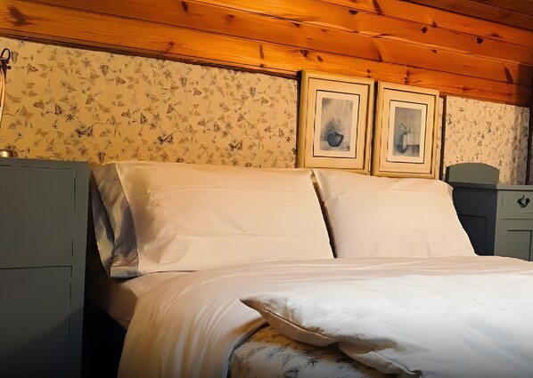 A bed with white linens in a room with wooden ceiling and floral wallpaper. - Apartment 'Al Piccolo Principe -Rosa' with Mountain View, Shared Garden and Wi-Fi (Cles)