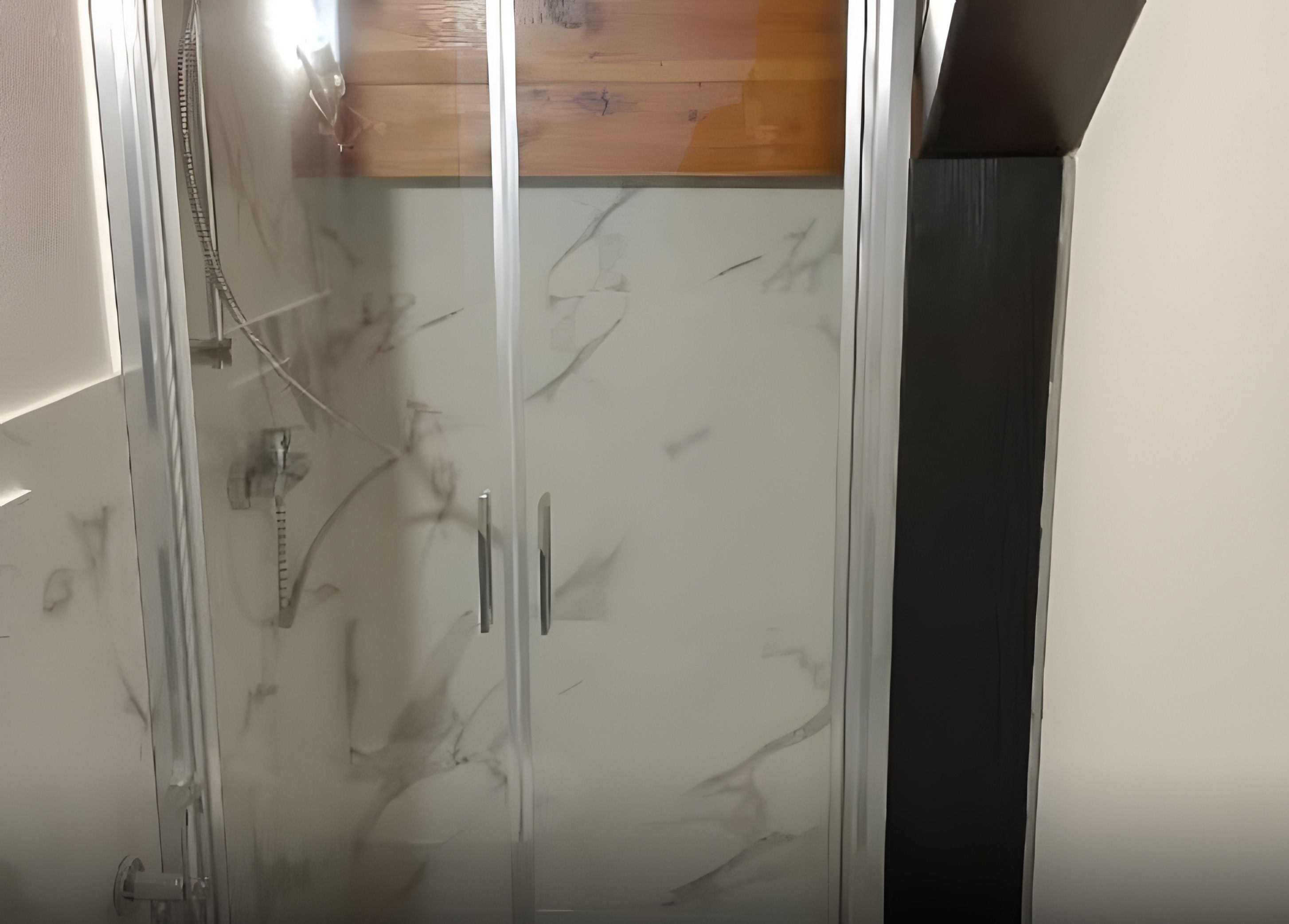 Ein Badezimmer mit einer Duschkabine aus Glas, einer Holzvertäfelung über der Dusche und einer Wand mit weißen Fliesen.