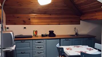 Una cocina compacta con techo de madera, una mesa de comedor con sillas y una pequeña alfombra.