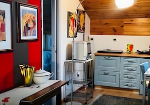 A kitchen with a wooden ceiling, a refrigerator, a sink, and a countertop with a kettle and a cup. - Apartment 'Al Piccolo Principe -Rosa' with Mountain View, Shared Garden and Wi-Fi (Cles)