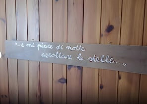A wooden wall with a metal plaque that reads '...e mi piace di notte ascoltare la stella...'. - Apartment 'Al Piccolo Principe -Rosa' with Mountain View, Shared Garden and Wi-Fi (Cles)