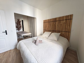 Un dormitorio con cama, mesita de noche, espejo y puerta.