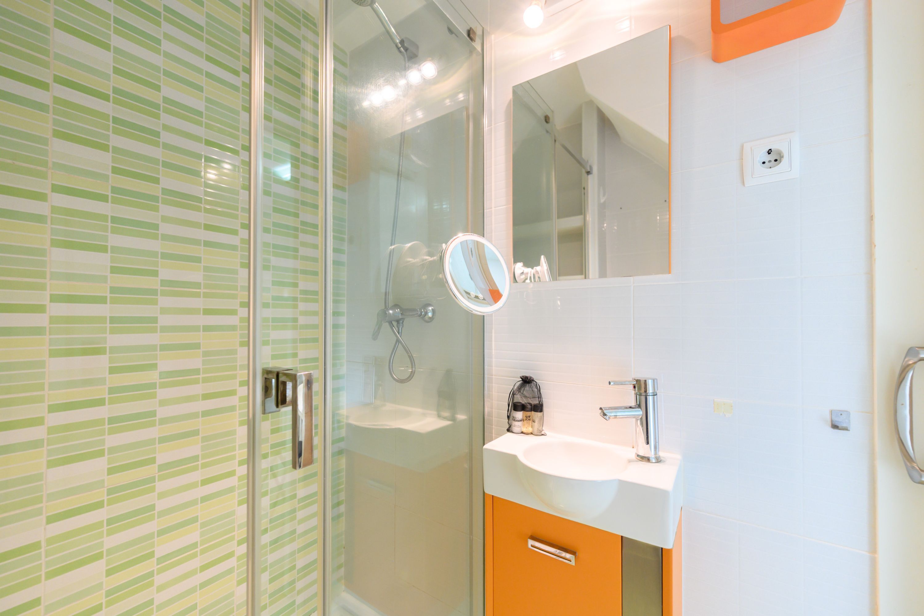 Un bagno con box doccia in vetro, un lavandino bianco e uno specchio.