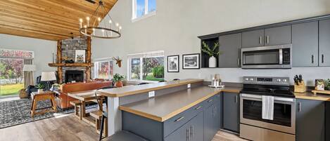 A modern kitchen with a central island, stainless steel appliances, and a dining area with a fireplace.