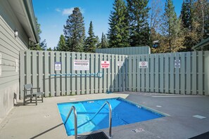 A swimming pool with a wooden fence, a lifeguard chair, and multiple warning signs. - Hidden Village Haven (Big Sky)