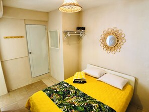 Quarto com cama, mesa de cabeceira, espelho e luminária suspensa.