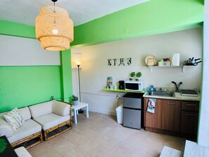 Um espaço compacto com cozinha compacta, área de jantar com sofá e uma pequena mesa.