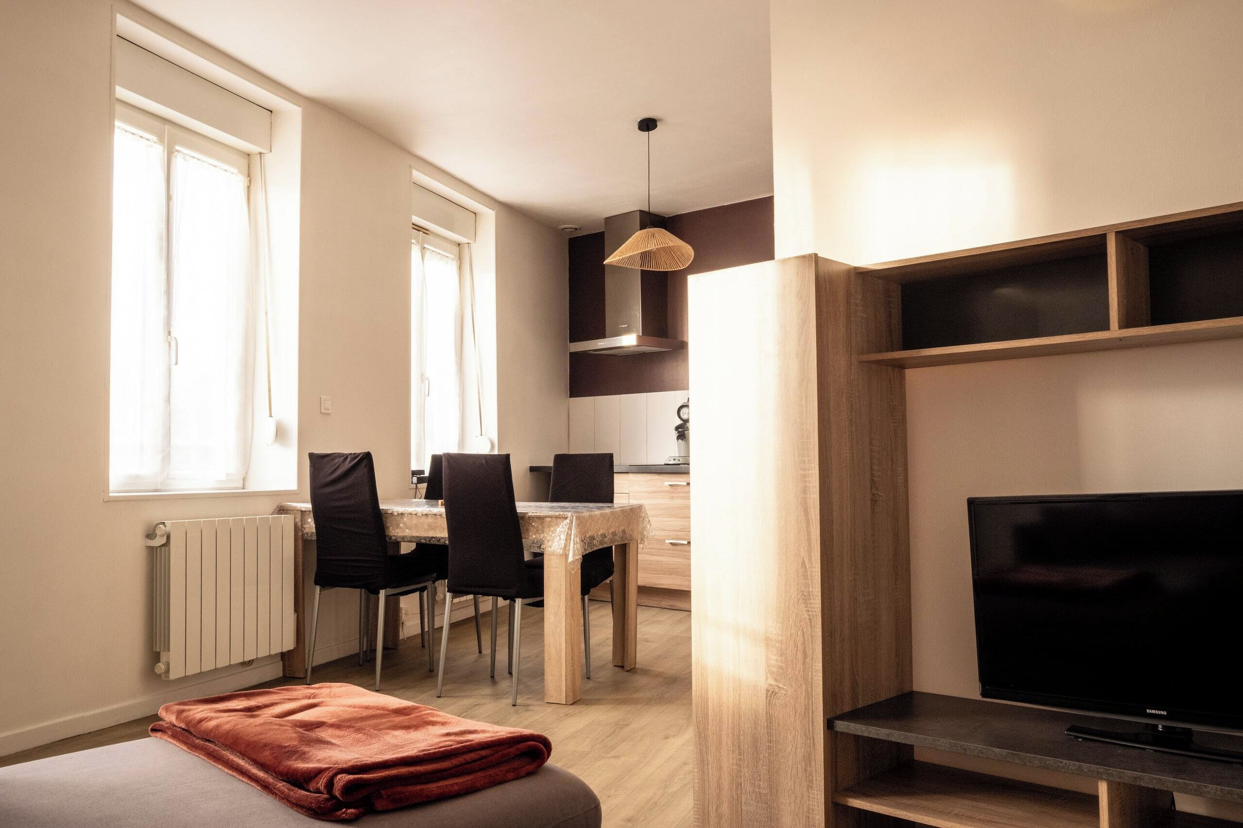A compact living space with a dining area, a television, and a radiator.