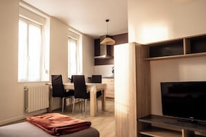 A compact living space with a dining area, a television, and a radiator. - Entire duplex apartment (Bourbourg)