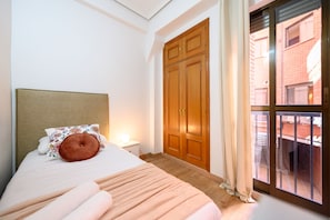 A bedroom with a bed, a nightstand, a wooden wardrobe, and a window with curtains. - M Adu151a Piso 2 Dormitorios en Sol Centro de M (Madrid)