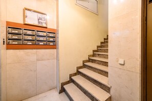 A staircase with a marble floor leading to a landing with a wooden shelf holding mailboxes. - M Adu151a Piso 2 Dormitorios en Sol Centro de M (Madrid)