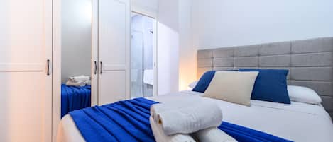 Ett hotellrum med en säng, en garderob och ett badrum som syns genom en öppen dörr.