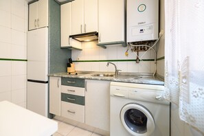 A compact kitchen with white cabinets, a built-in washing machine, and a sink. - M Adu151a Piso 2 Dormitorios en Sol Centro de M (Madrid)