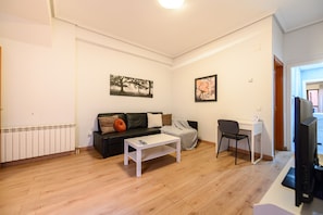 Una sala de estar con sofá, mesa de centro, televisor y escritorio.