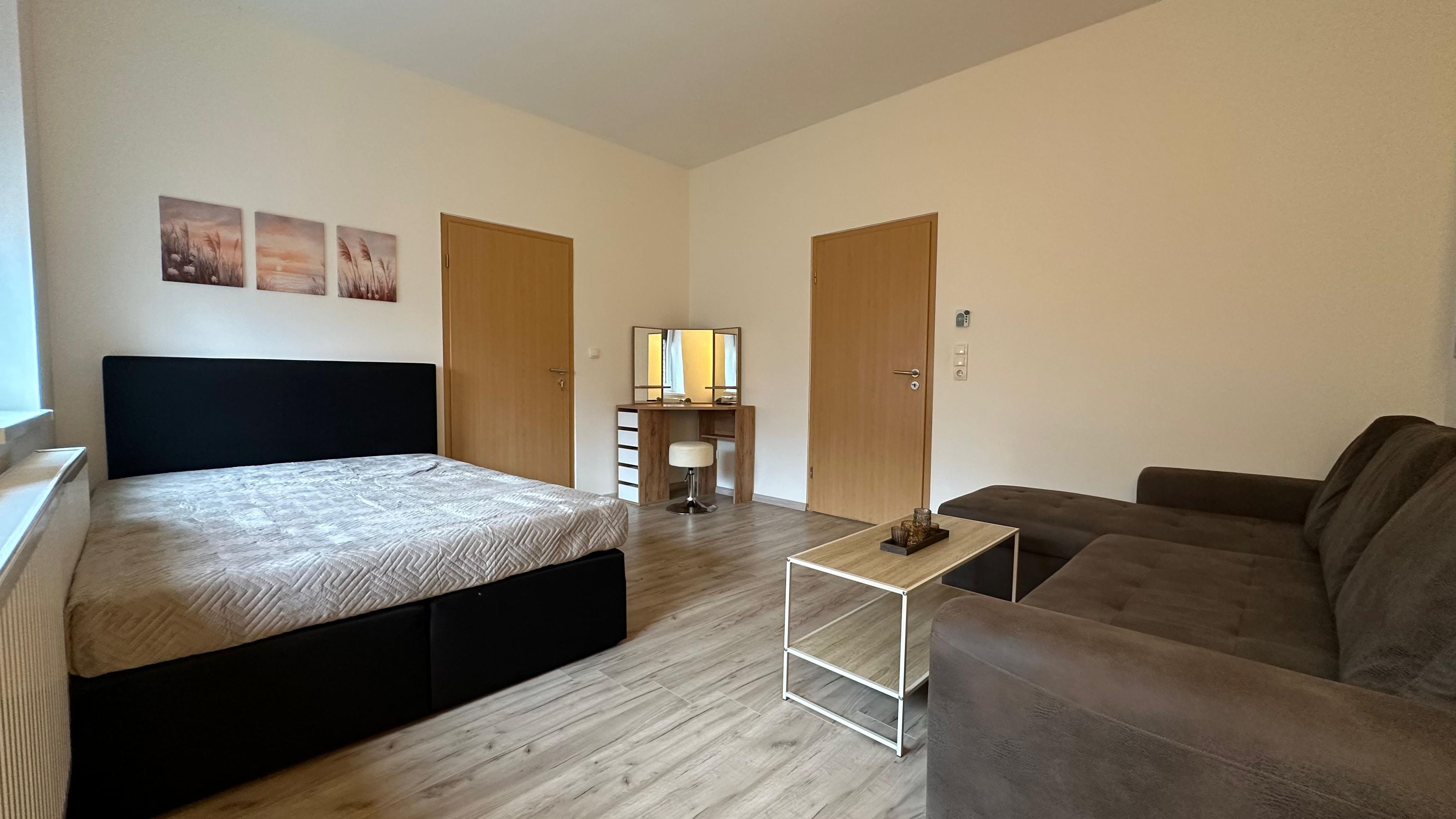 Une chambre à coucher avec un lit, une table de chevet, un miroir, une commode et une fenêtre.