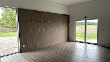 A spacious room with a wooden floor, a vertical garden wall, and a large sliding glass door leading to an outdoor area.